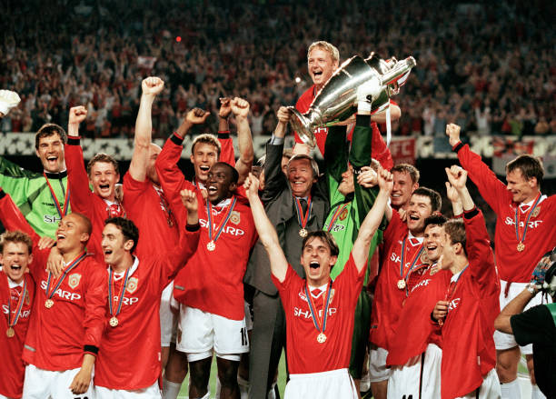 Manchester United vs. Bayern Munich (1999 Champions League Final) greatest football matches ever BARCELONA, SPAIN - MAY 26: Manchester United manager Alex Ferguson with his players as they celebrate with the trophy during the presentation after winning the UEFA Champions League Final between Manchester United and Bayern Munich at Camp Nou on May 26, 1999 in Barcelona, Spain. Manchester United won 2-1.