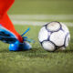 Countries that call football soccer Blurred motion shot of a football player wearing shin guards and cleats winding up to kick a soccer ball on a grass field during important championship football game