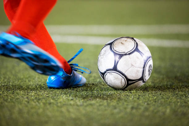 Countries that call football soccer Blurred motion shot of a football player wearing shin guards and cleats winding up to kick a soccer ball on a grass field during important championship football game