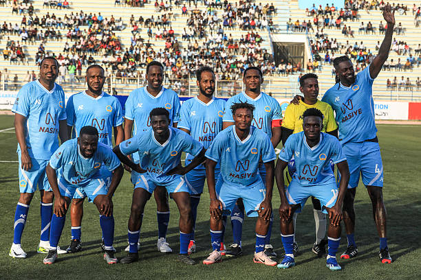 Retired football stars Nigerian Jay-Jay Okocha (2L back), Cameroonian Samuel Eto'o (5thL back) and Togolese Emmanuel Adebayor (R back), pose for a photo with members of an exhibition team ahead of a FIFA-backed match between an international side and a local team at the National Stadium in Mogadishu on May 27, 2025. Three African football legends -Samuel Eto'o, Emmanuel Adebayor and Jay-Jay Okocha- took to the pitch in Somalia on May 27, 2025 for an exhibition match aimed at restoring the image of the country, in a state of near-constant internal conflict since 1991. The three superstars were part of a FIFA-backed "peace tour" that Somalia hopes will help it once again host international fixtures
